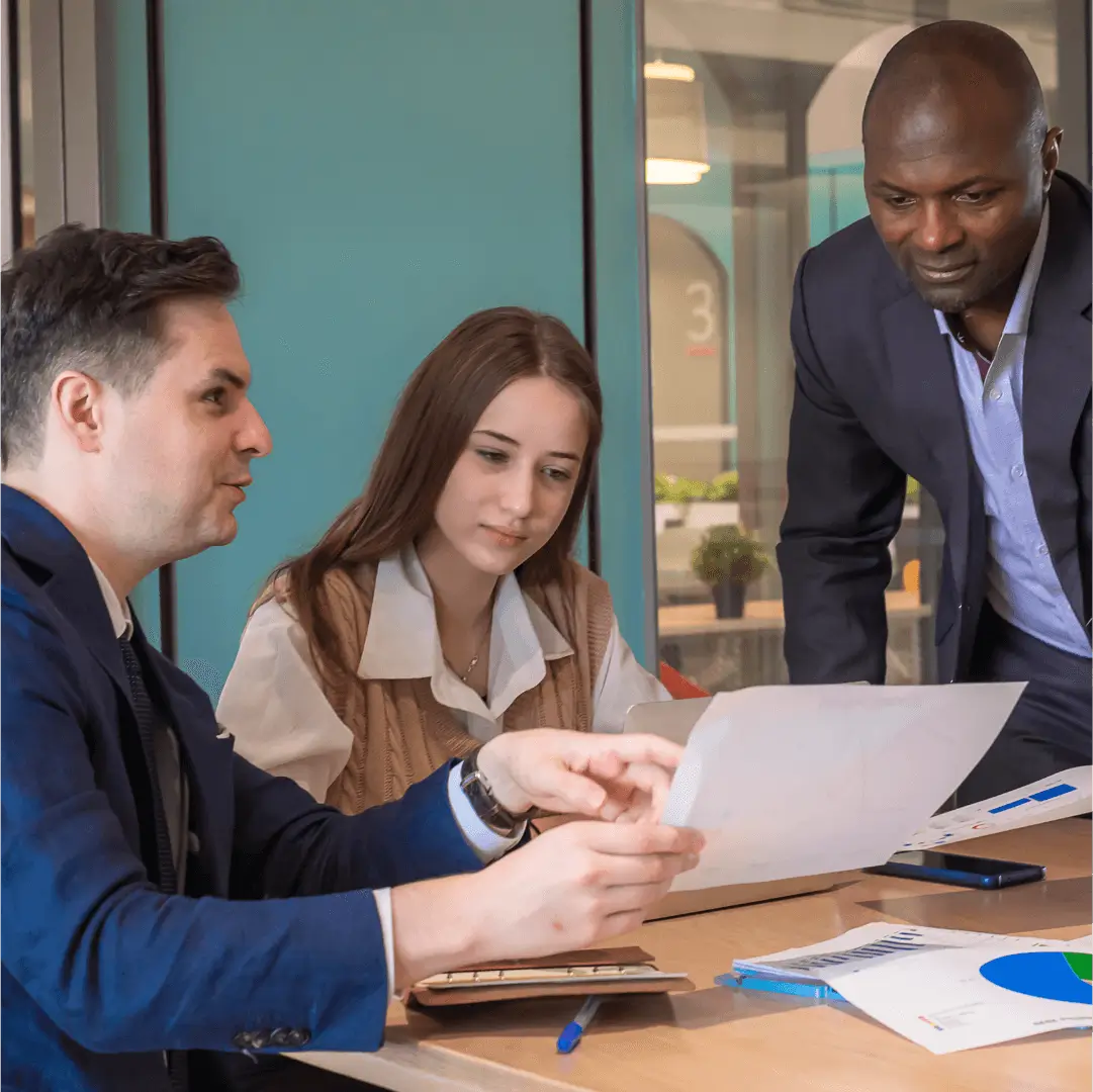 Three business professionals discussing documents at a table.