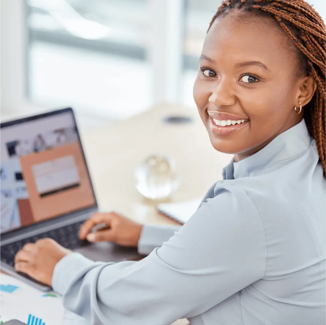 Smiling woman working on laptop in office.